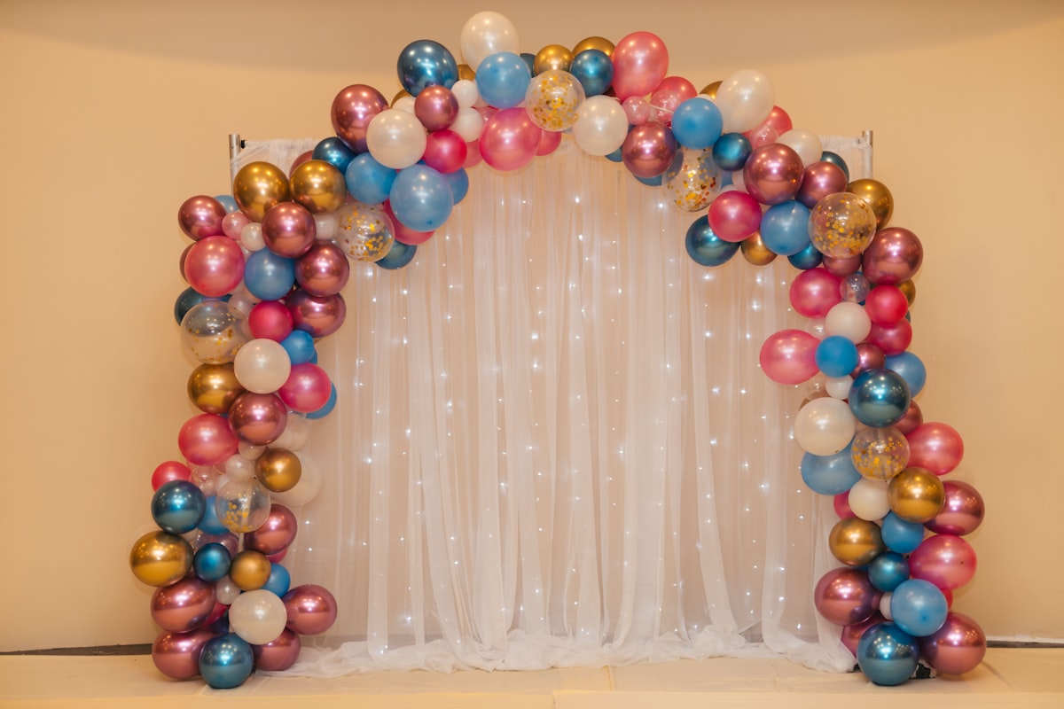 Multicolored balloon arrangement near white curtain for event stage