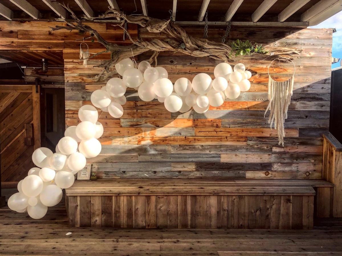 White balloon garland installation on brown wooden ceiling